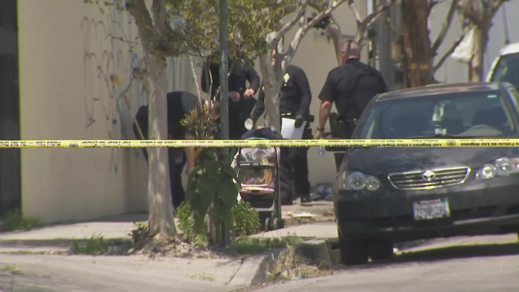 Police investigate a shooting behind yellow crime scene tape.